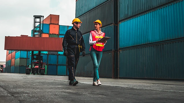 2 people walking in the middle of containers
